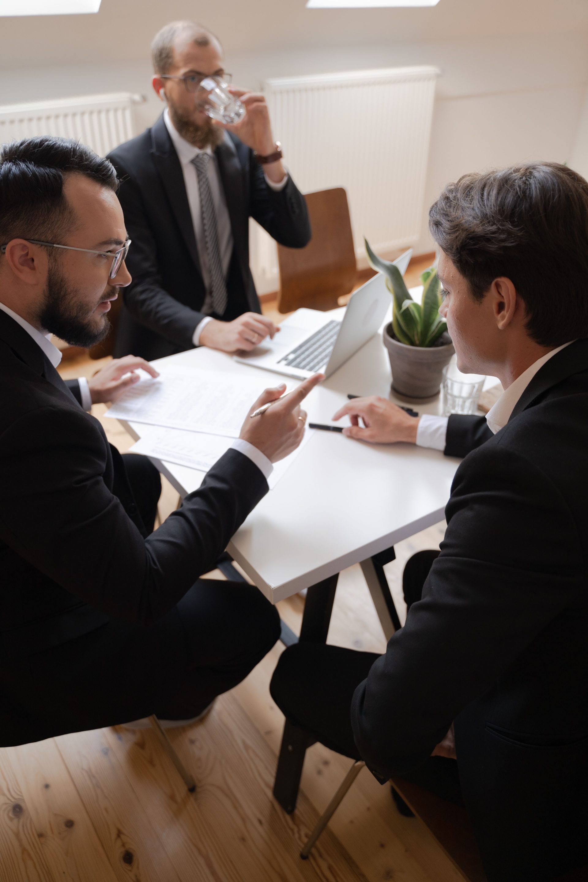 Drei Geschäftsleute führen während einer formellen Besprechung in einem Büro ein Gespräch.